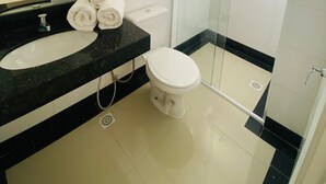 A modern bathroom with a black countertop, white sink, and toilet. There are three rolled towels on the countertop. - Kleinville Marquês (Sao Leopoldo)