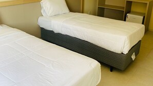 A hotel room with two single beds, a wardrobe, and a bedside table with a lamp. - Kleinville Marquês (Sao Leopoldo)