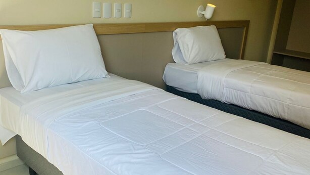 Two single beds with white bedding in a hotel room. - Kleinville Marquês (Sao Leopoldo)