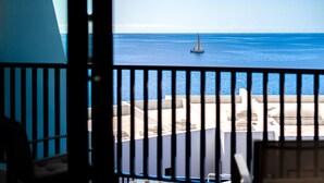 A balcony with a view of the sea and a sailboat.