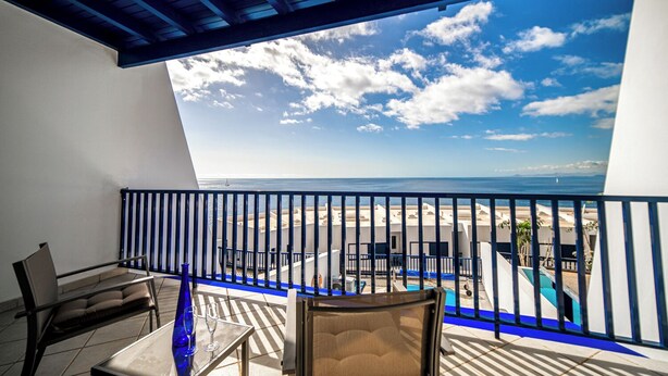 A balcony with a view of the beach and ocean.