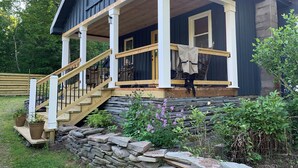 Ein Haus mit einer Holzveranda, einer Steismauer und einer Treppe, die zum Eingang führt.
