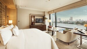 Hotelkamer met een groot bed, een bureau met stoel, een televisie en uitzicht op een stadshemel en rivier.