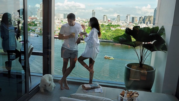 Een moderne hotelkamer met een groot raam met uitzicht op een stadsbeeld en een rivier.