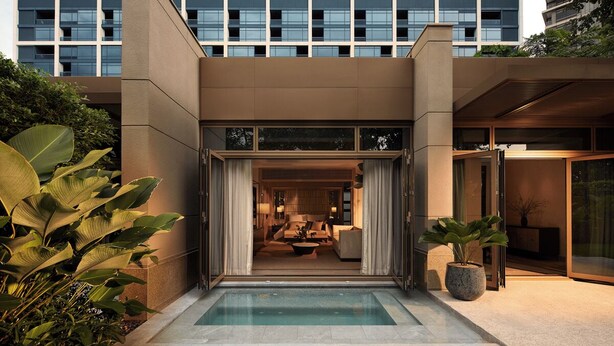 Un edificio moderno con piscina, ventanas amplias y un jardín bien cuidado.