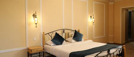 Un dormitorio con cama, mesitas de noche y apliques de pared.