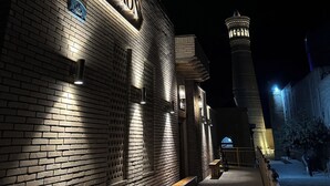 A brick building with a sign reading "ZARGAROU Boutique Hotel" at night. - Zargaron Boutique Hotel (Bukhara)