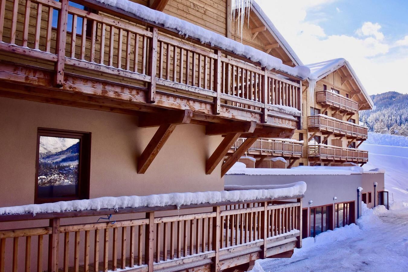 A wooden chalet with multiple balconies and a snowy landscape.
