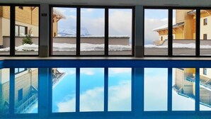 A swimming pool with a view of snowy mountains and buildings. - Ski-in/ski-out & foot of the slopes, swimming pool, terrace, balcony, tv, 35m², Combloux (Combloux)