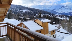 Une cabane en bois dotée d’un balcon donnant sur un paysage montagneux enneigé.