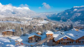 Ein schneebedecktes Bergresort mit Holzhütten und einer Seilbahn.