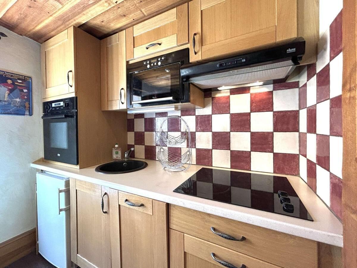 Une cuisine compacte avec des meubles en bois, un four encastré, un four à micro-ondes et une cuisinière à gaz.