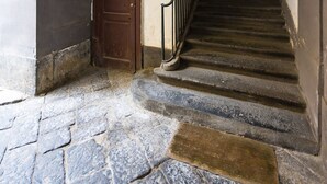 A stone staircase with a wooden door at the top, leading to a room with a window and a light fixture. - Bisignano 11 in Naples (Naples)