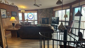 A cozy living room with a wooden floor, a sofa, a TV, and a dining area with a table and chairs.