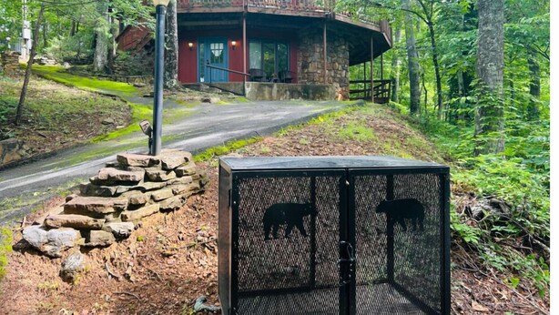 A rustic cabin with a stone exterior, a balcony, and a fenced enclosure with animal silhouettes.