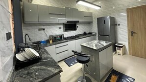 A modern kitchen with marble countertops, stainless steel appliances, and a built-in oven. - The Jericho Apartments (Ibadan)