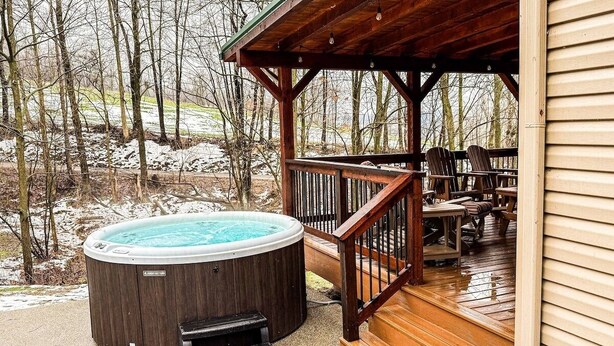 Een houten terras met een jacuzzi en een zitgedeelte buiten.