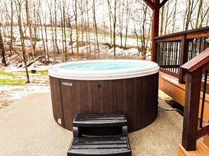 Un bain à remous doté d’une terrasse en bois et d’un escalier en bois menant à celui-ci.
