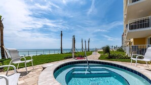 A swimming pool with lounge chairs, a view of the ocean, and a building with balconies. - Unit 203 Aruba - 3 Bedroom Ocean Front (Daytona Beach Shores)