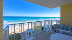 A balcony with a view of the ocean, white furniture, and a yellow wall. - Unit 203 Aruba - 3 Bedroom Ocean Front (Daytona Beach Shores)