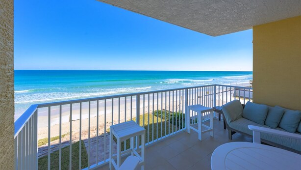 A balcony with a view of the ocean, white furniture, and a yellow wall. - Unit 203 Aruba - 3 Bedroom Ocean Front (Daytona Beach Shores)