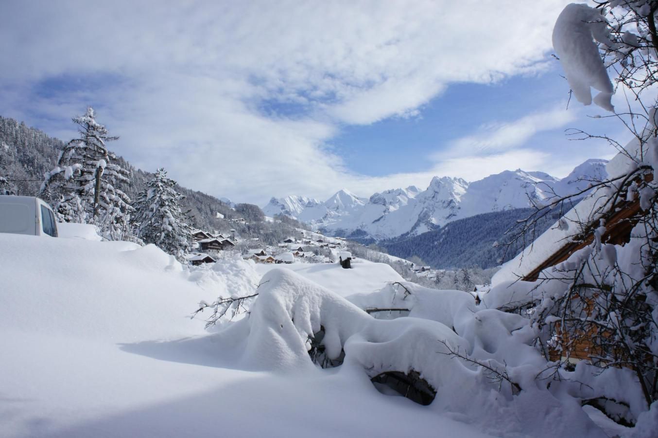 A snowy mountain landscape with a clear sky, snow-covered trees, and a distant view of mountains.