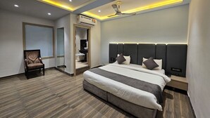 A modern bedroom with a large bed, a ceiling fan, recessed lighting, and a walk-in closet. - Hotel MK Vivanta (Gwalior)