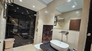 A modern bathroom with a black marble vanity, a white sink, and a glass shower enclosure. - Hotel MK Vivanta (Gwalior)