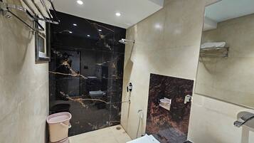 Un baño moderno con tocador de mármol negro, lavamanos blanco y zona de ducha.