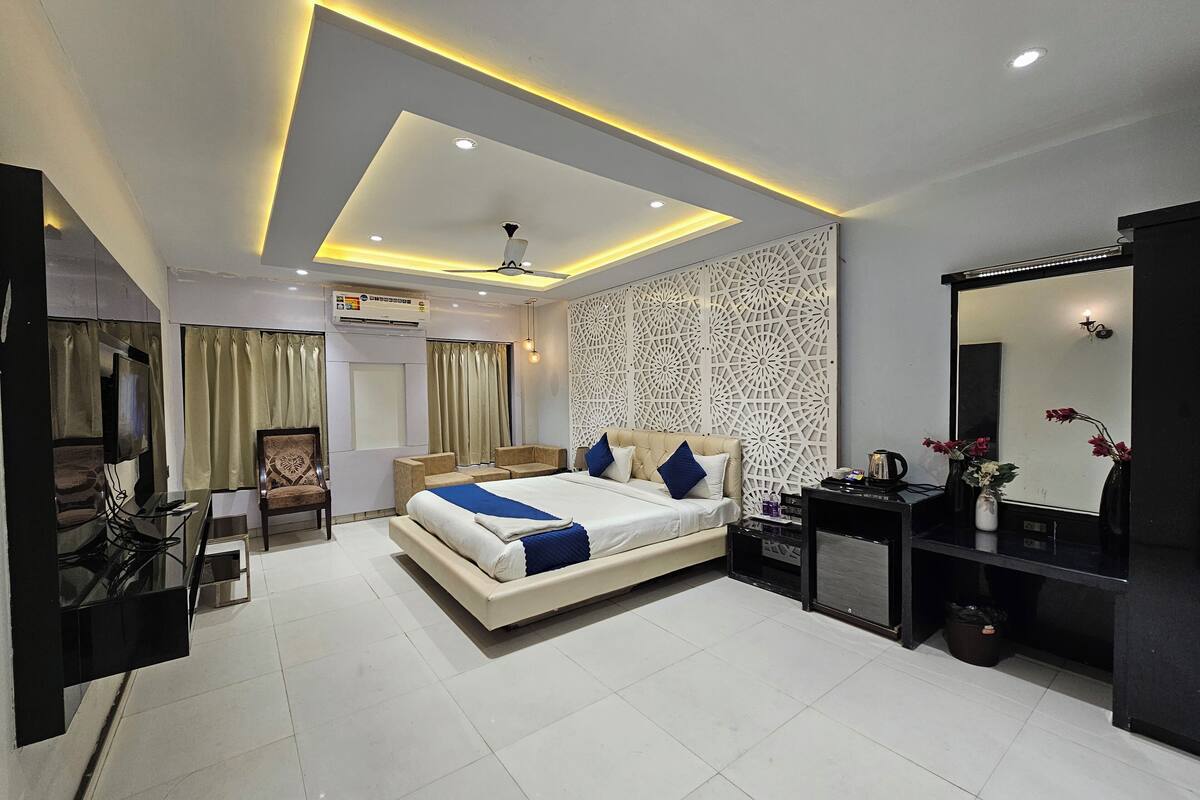 A modern bedroom with a large bed, bedside tables, a desk, and a TV.