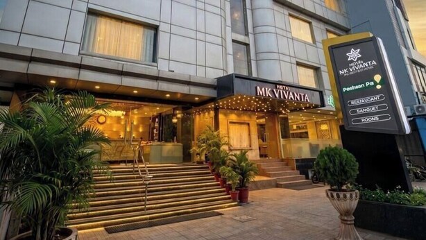 A multi-story hotel with a modern facade, a prominent entrance with steps, and signage indicating amenities like a restaurant, bar, and rooms. - Hotel MK Vivanta (Gwalior)