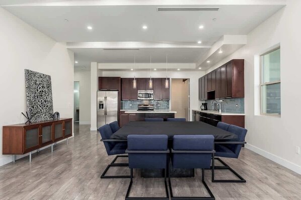 A modern kitchen with dark wooden cabinets, a central island, and pendant lighting.