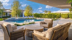 A poolside area with wicker furniture, a clear view of the pool, and a modern building in the background.