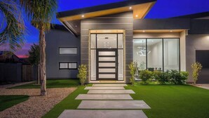 A modern house with a well-maintained lawn, a pathway leading to the entrance, and a large window on the right side.