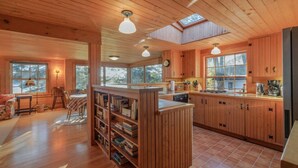 A spacious cabin with wooden interiors, a central island with a sink, and a bookshelf.