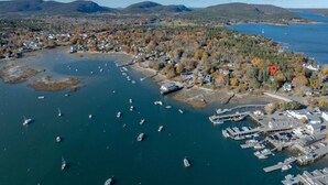 An aerial view of a coastal town with a marina, boats, and houses.