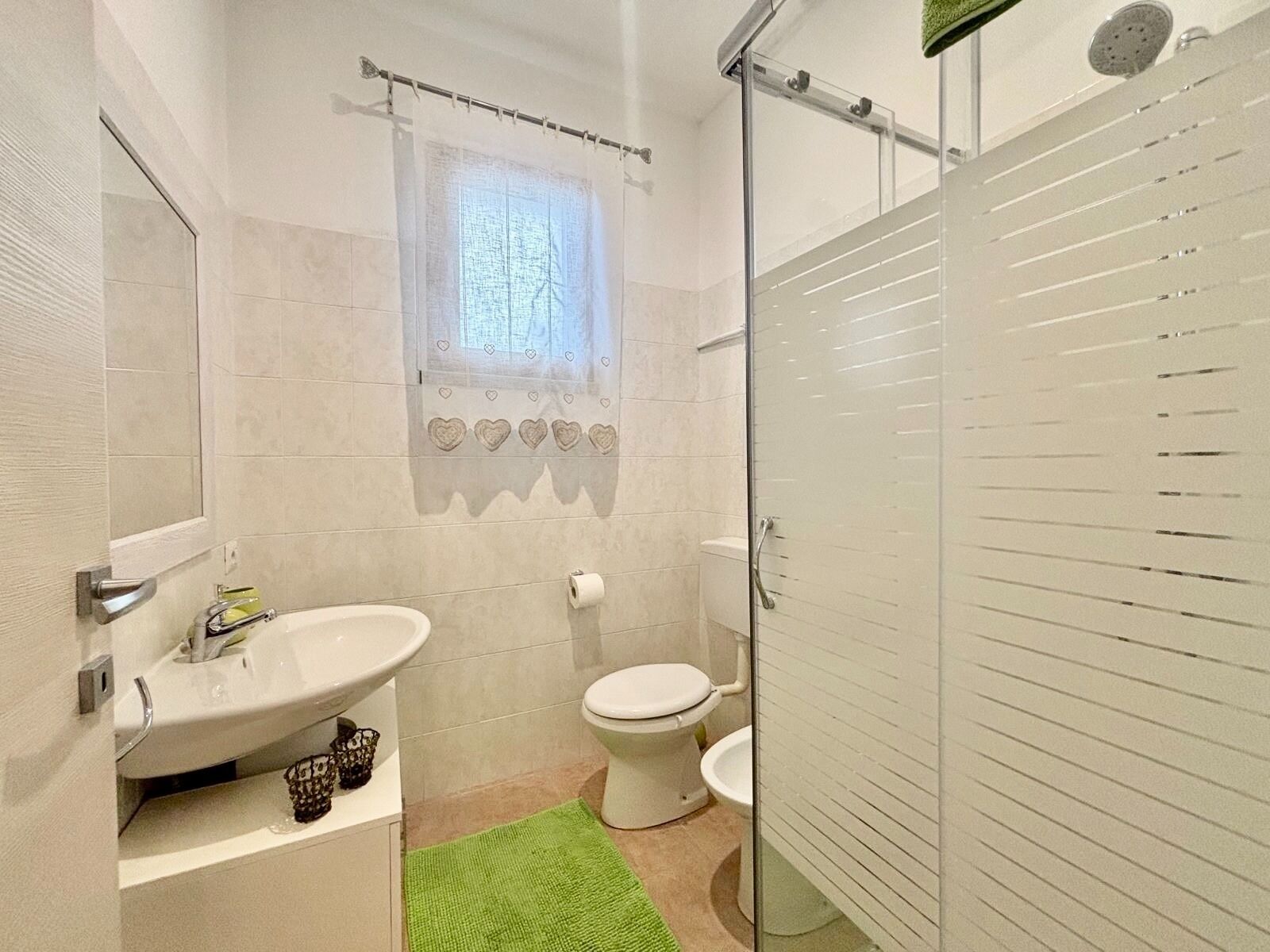 Une salle de bain avec un lavabo, des toilettes et une douche, le tout de couleur blanche.