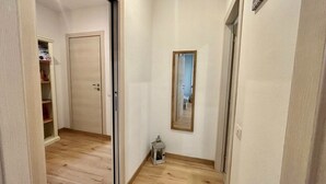 A narrow hallway with wooden flooring, a door on the left, and a mirror on the right. - Cozy apartment, 10 min. from Alghero, ideal for families (Olmedo)