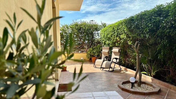 An outdoor patio area with tiled flooring, two lounge chairs, and a small tree in a planter. - Cozy apartment, 10 min. from Alghero, ideal for families (Olmedo)