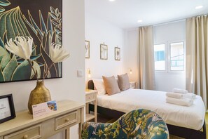 Une chambre d’hôtel avec un lit, une table de chevet, une lampe et un grand tableau représentant des fleurs.