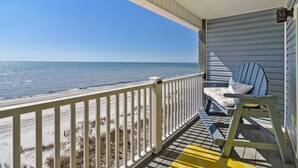 A beach view from a porch with a white railing, a blue chair, and a wooden ladder. - Gulf-front! Beachfront! Directly on the Sand! New Boardwalk! Amazing Ocean View! (Mexico Beach)