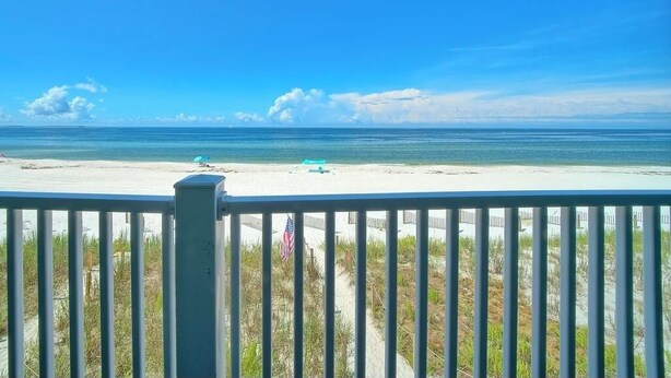 A beach view from a balcony with a railing, a sandy beach, and a clear sky. - Gulf-front! Beachfront! Directly on the Sand! New Boardwalk! Amazing Ocean View! (Mexico Beach)