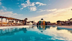 Una piscina con lettini e uno scivolo acquatico.