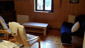 Un accogliente chalet con interni in legno, una panca, un divano e un televisore.