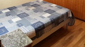 Una stanza con pareti in legno, un letto con copriletto e una lampada a sospensione, oltre a un quadro appeso al muro.