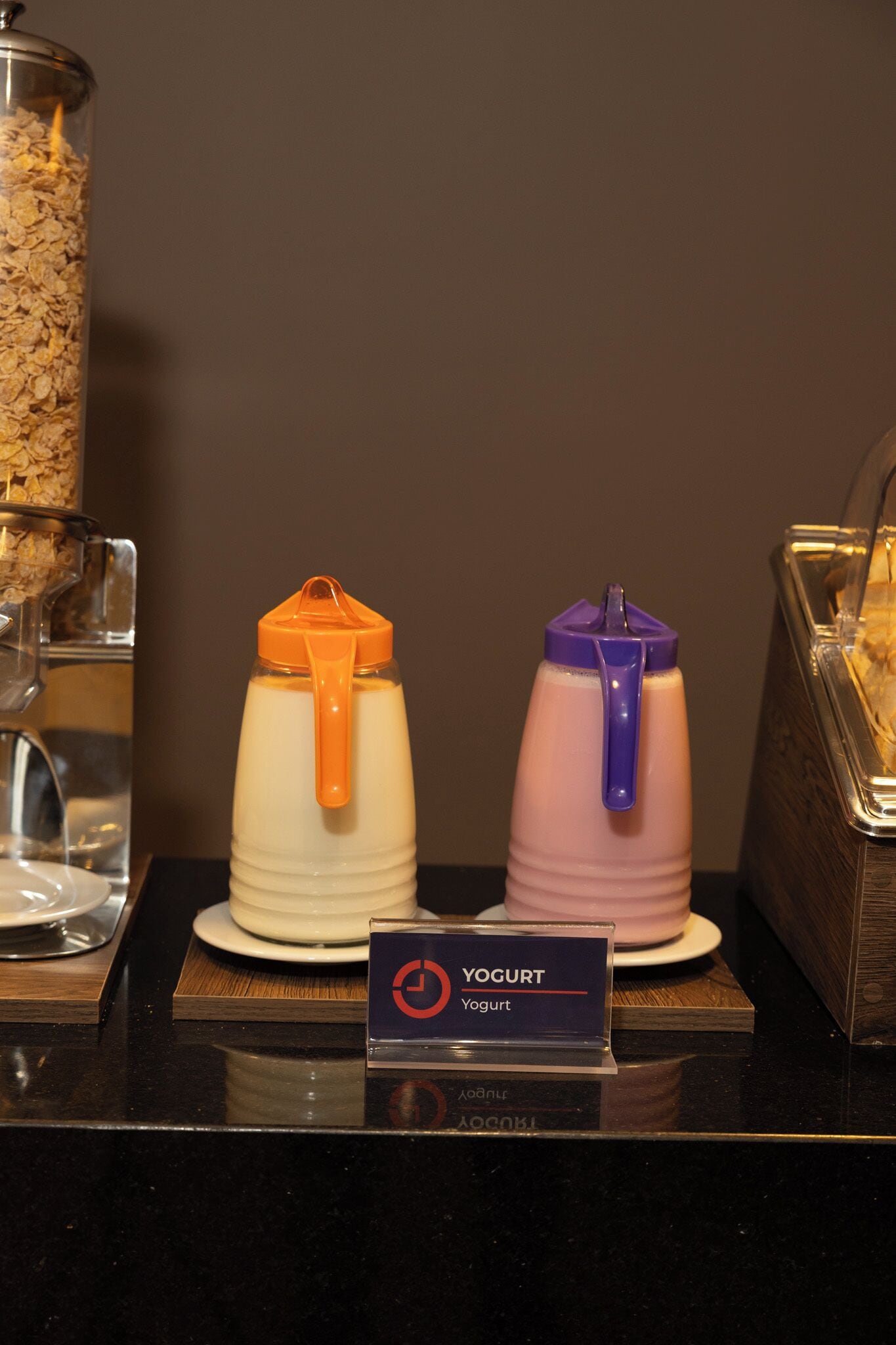 A yogurt display with two containers, one orange and one purple, on a counter with a sign labeled "Yogurt."