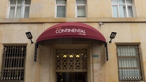 L’entrée d’un hôtel, avec un auvent bordeaux et une enseigne indiquant « Continental By Hours ».