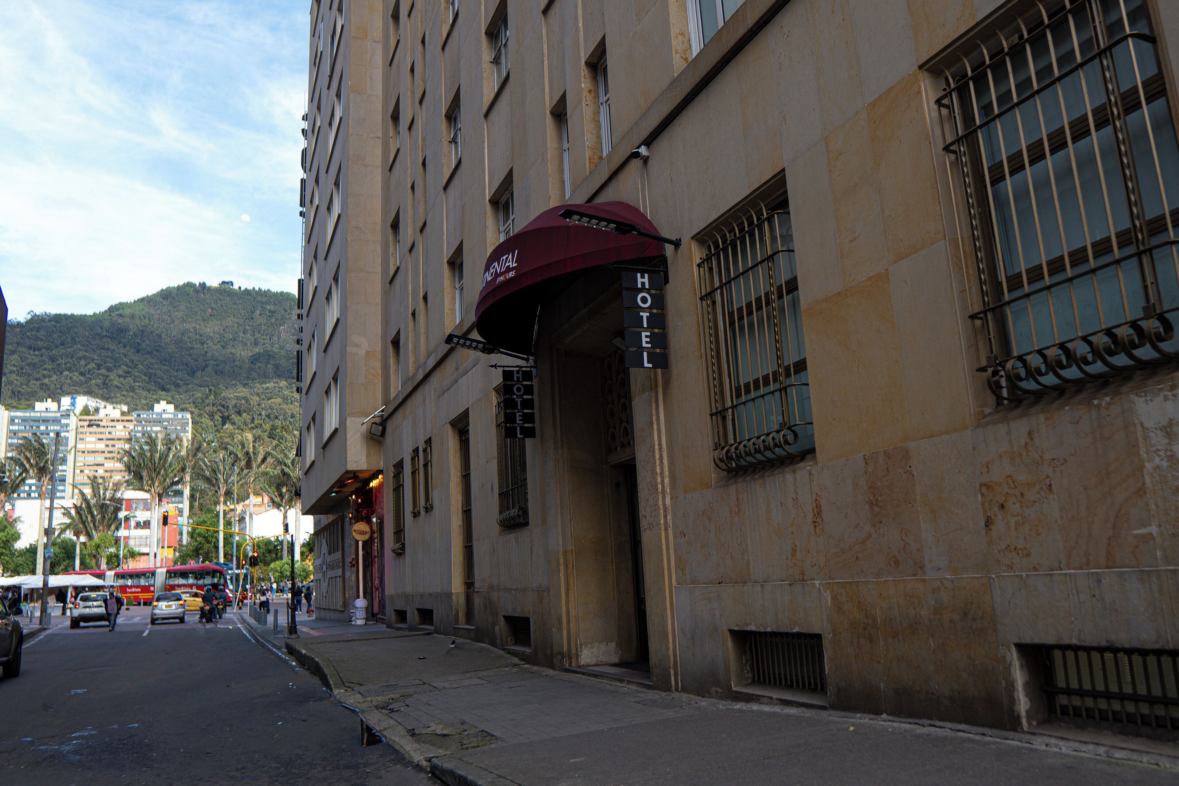 A hotel with a signboard, a street view, and a mountain in the background.