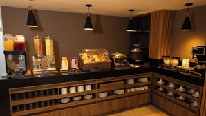 Un buffet de petit-déjeuner proposant une variété d’aliments et de boissons, notamment des céréales, des yaourts et des jus de fruits.