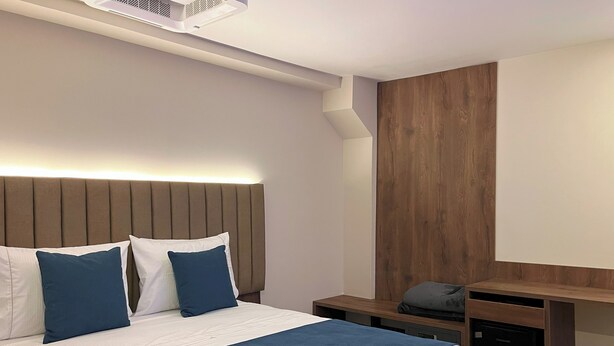 Une chambre d’hôtel moderne, dotée d’un grand lit, d’une tête de lit en bois, d’un bureau et d’un radiateur intégré.